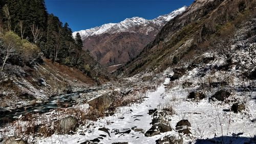 Scenic view of stream amidst snowcapped mountains against sky