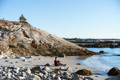 Rear view of people on rock by sea against sky