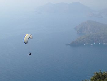 Person paragliding over sea against sky