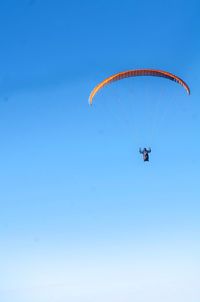 Low angle view of person paragliding against clear blue sky