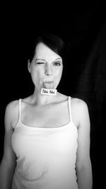 Portrait of young woman standing against black background