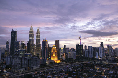 Illuminated cityscape against sky during sunset