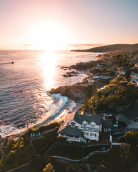 High angle view of sea and buildings against sky during sunset