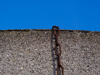 Low angle view of weathered wall against clear blue sky