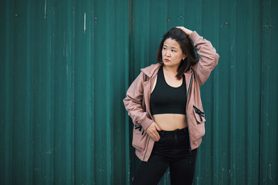 Young woman standing against yellow wall