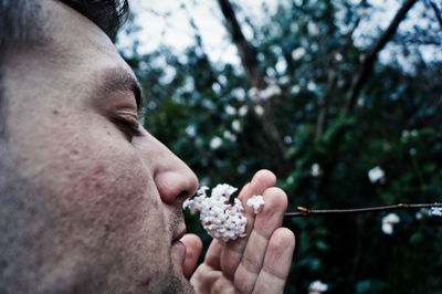 Close-up of man smelling flowers at yard