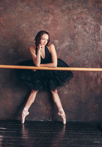 Full length of young woman dancing against wall