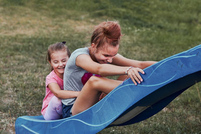 Siblings sitting on slide at playground