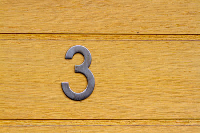 House number 3 on a natural grained wooden front door in london 