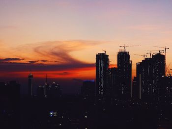 Silhouette buildings in city at sunset
