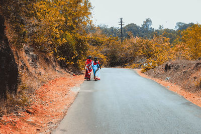 Rear view of women walking on road during autumn