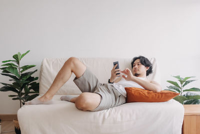 Young woman using phone while lying on bed at home