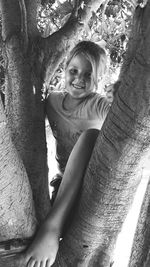 Portrait of smiling woman sitting on tree trunk