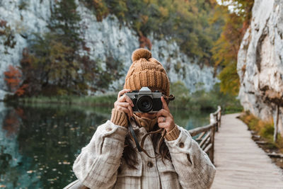 Portrait of young woman taking photos of beautiful autumn nature with a vintage film camera