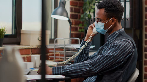 Businessman talking on telephone at office during pandemic