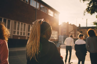 Rear view of people standing on street in city