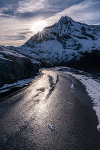 Road by snowcapped mountains against sky during winter