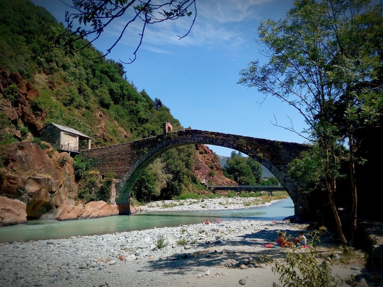 tree, connection, bridge - man made structure, tranquility, water, tranquil scene, nature, sky, scenics, beauty in nature, bridge, river, rock - object, arch, built structure, mountain, growth, branch, arch bridge, day