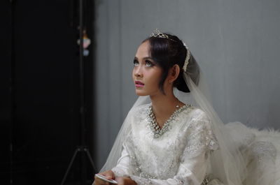 Bride sitting against wall