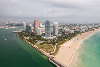 Aerial of south pointe high-rise buildings in miami beach with sandy shores lining turquoise waters.