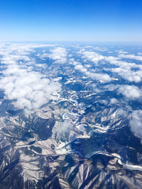 Aerial view of snowcapped mountains against blue sky