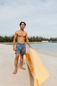 Portrait of shirtless man standing at beach