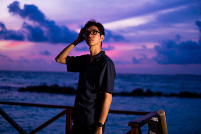 Man standing by sea against sky during sunset