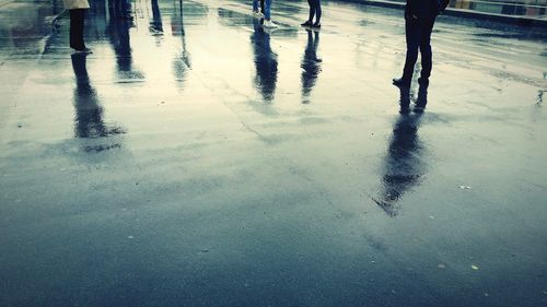 Low section of people walking on wet road during rainy season