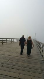 Rear view of woman standing on footbridge
