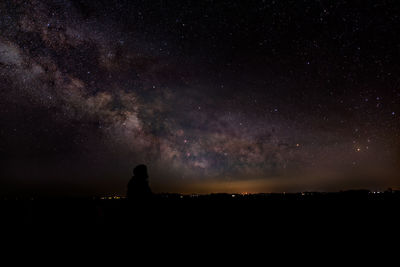 Silhouette woman against star field at night