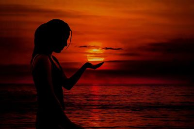 Silhouette woman standing at beach during sunset