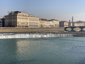 Arch bridge over river against buildings in city