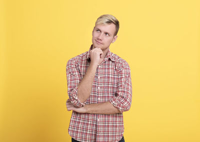 Portrait of mid adult man against yellow background