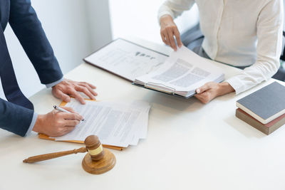 Midsection of lawyer with client working at office