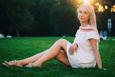 Portrait of beautiful woman sitting on grassy field at park