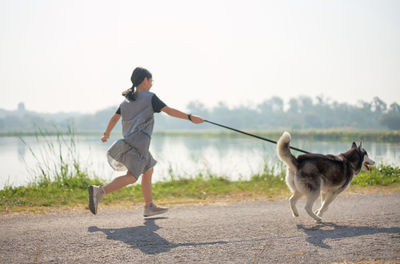 Full length of girl with dog running on road