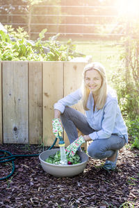 Portrait of woman washing root vegetables in basket at garden