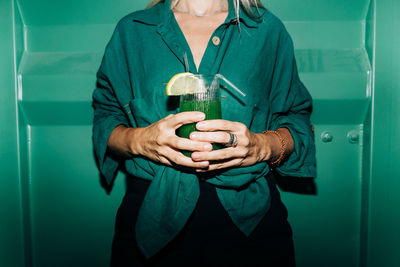 An unrecognizable woman holds a cool cocktail in her hands.