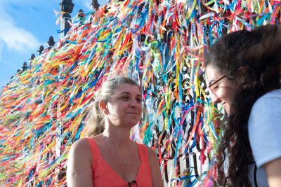 Portrait of two women placing colored ribbons on the church grid. 