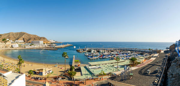 High angle view of townscape by sea against clear blue sky