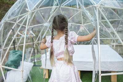 Rear view of woman holding girl standing outdoors