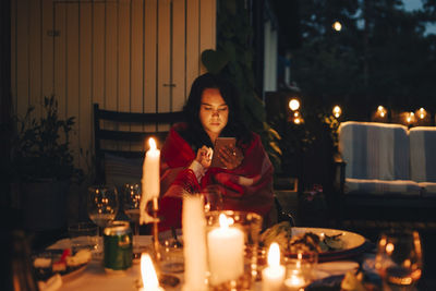 Young woman using mobile phone at dining table