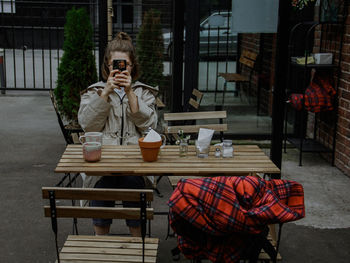 Full length of woman sitting on table at cafe