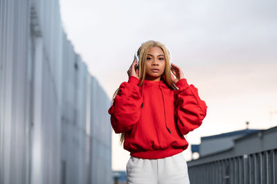 Cheerful african american woman with long blonde hair wearing sportswear and wearing headphones