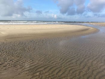 View of calm beach against cloudy sky