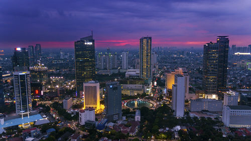 Illuminated cityscape against sky at dusk