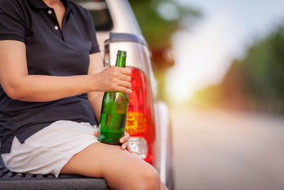 Midsection of man sitting in glass bottle