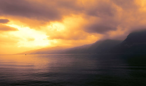 Scenic view of sea against dramatic sky during sunset