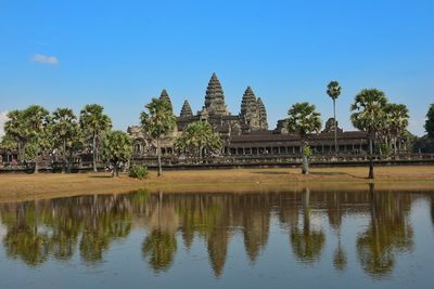 Pond in front of angkor wat against clear blue sky