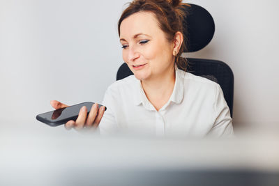 Woman talking on smartphone using speaker mode recording audio message using voice assistance